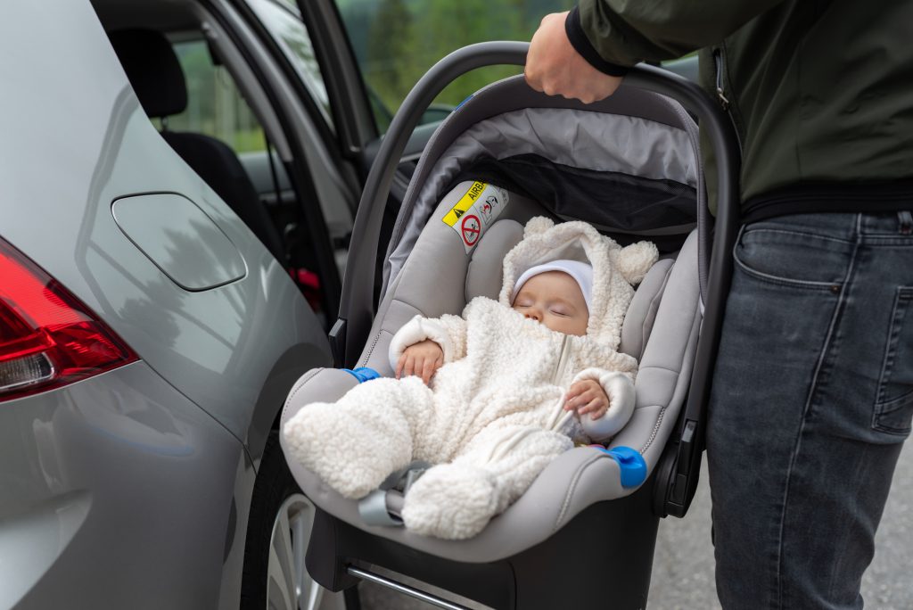 Adorable infant in car seat carried by dad.